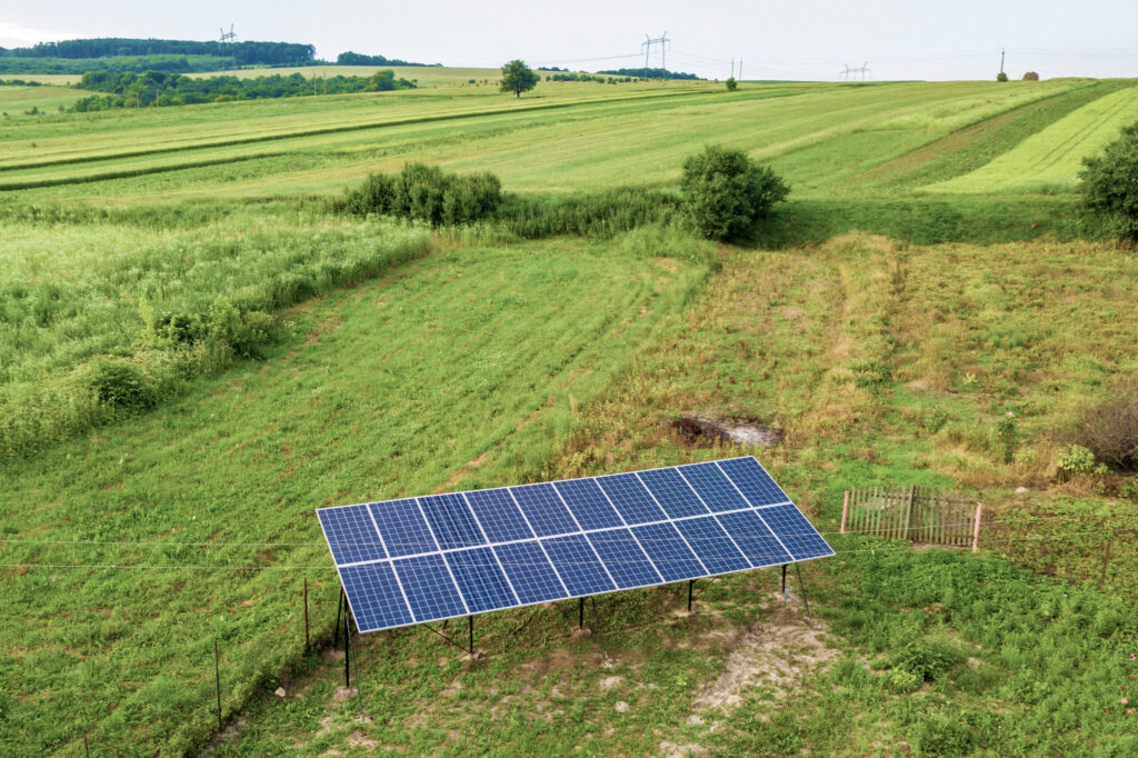 Luftaufnahme von oben nach unten von Sonnenkollektoren in grüner ländlicher Umgebung.